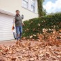 Mann benutzt Stihl Akku-Laubbläser BGA 50 zum Entfernen von Laub vor einem Haus.
