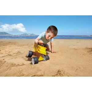 Kind spielt mit gelbem Hape Sandspielzeug Kipper am Strand.