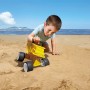 Kind spielt mit gelbem Hape Sandspielzeug Kipper am Strand.