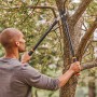Mann schneidet Ast mit Fiskars Bypass-Astschere L11. Gartenschere mit Antihaftbeschichtung.