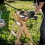 Person sägt Holz mit Metabo Akku-Gehölzsäge MS 18 LTX 15 auf einem Sägebock. Schubkarre mit Holz im Hintergrund.