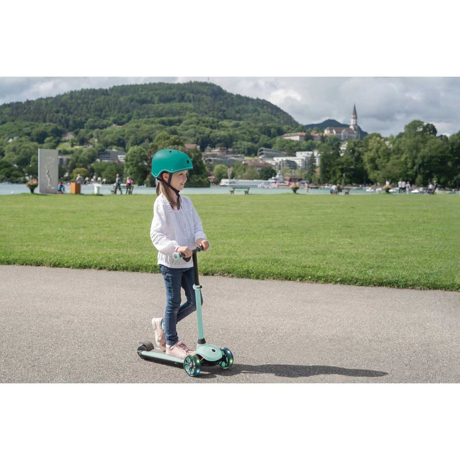Mädchen auf mintfarbenem Globber E-Scooter One K E-Motion 4 Plus mit LED-Rollen.