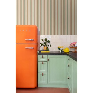 ESTAhome Vliestapete mit vertikalen Streifen in Grün und Braun, an einer Küchenwand mit orangefarbenem Kühlschrank und mintgrünen Schränken.