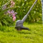 Gardena Akku-Rasentrimmer EasyTrim 25/18V im Einsatz, schneidet Rasen vor Blumenbeet.