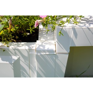 Detailansicht der weißen KHW Gartenbank Berlin mit Pflanzkästen und Bepflanzung.