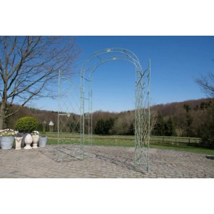 Antik-grüner Metall-Rosenbogen mit Tor als Rankhilfe und Gartendekoration auf gepflastertem Weg im Garten.