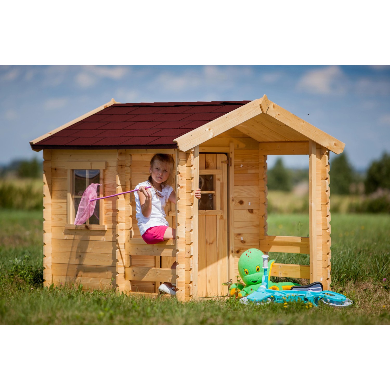 Timbela Kinderspielhaus M501A aus Holz mit Mädchen am Fenster und Spielzeug davor.