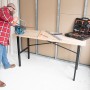rikta Werkbank 159 cm mit Person beim Sägen und Werkzeugkoffer im Hintergrund.