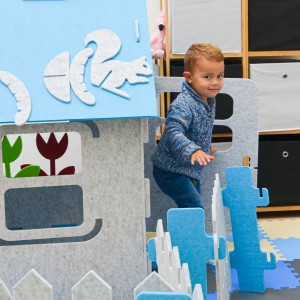 Blaues smalla Kinder Spielhaus aus Filz mit Zubehör und spielendem Kind.