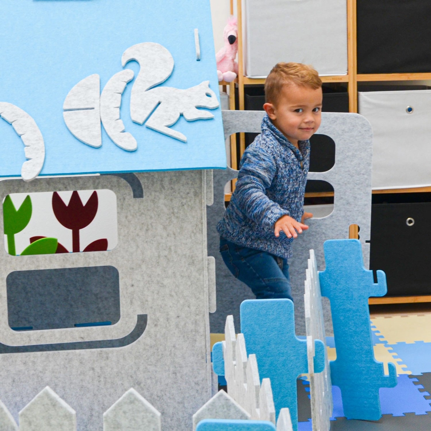 Blaues smalla Kinder Spielhaus aus Filz mit Zubehör und spielendem Kind.