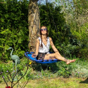 Dunkelblaue Relaxdays Nestschaukel, viereckig, mit Person im Garten, belastbar bis 100 kg.