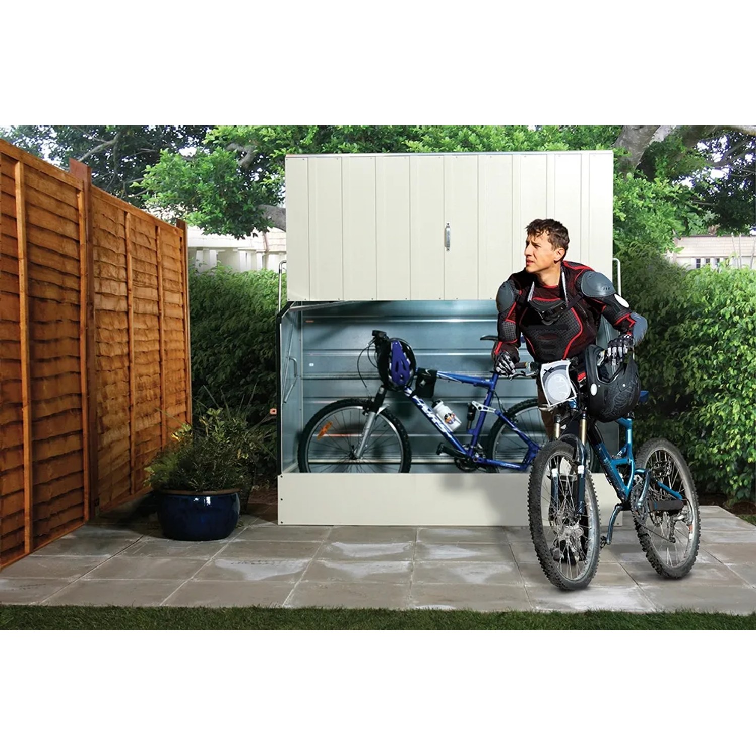 Duramax Fahrradbox in Hellbeige mit zwei Fahrrädern und einer Person davor im Garten.