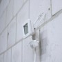 Weißer LED-Außenstrahler mit Sensor (10W, 1100lm, 4000K) an einer Wand montiert.