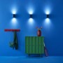 Drei schwarze WiZ LED Wandleuchten Up&Down an blauer Wand. Smarte Leuchten mit tunable White & Color, 690 lm.