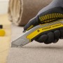 Stanley FatMax Messer Exo schneidet Teppich, mit Handschuh gehalten.