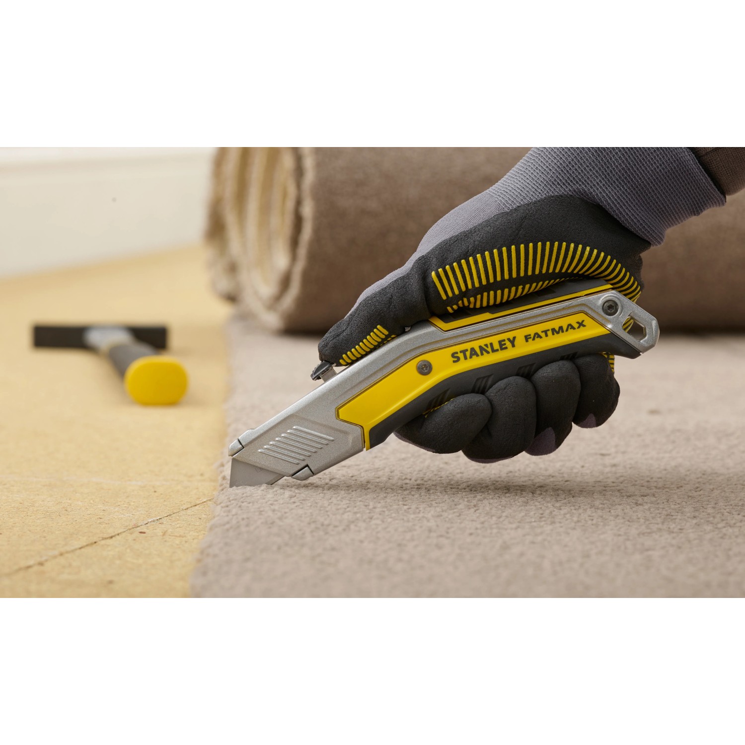 Stanley FatMax Messer Exo schneidet Teppich, mit Handschuh gehalten.