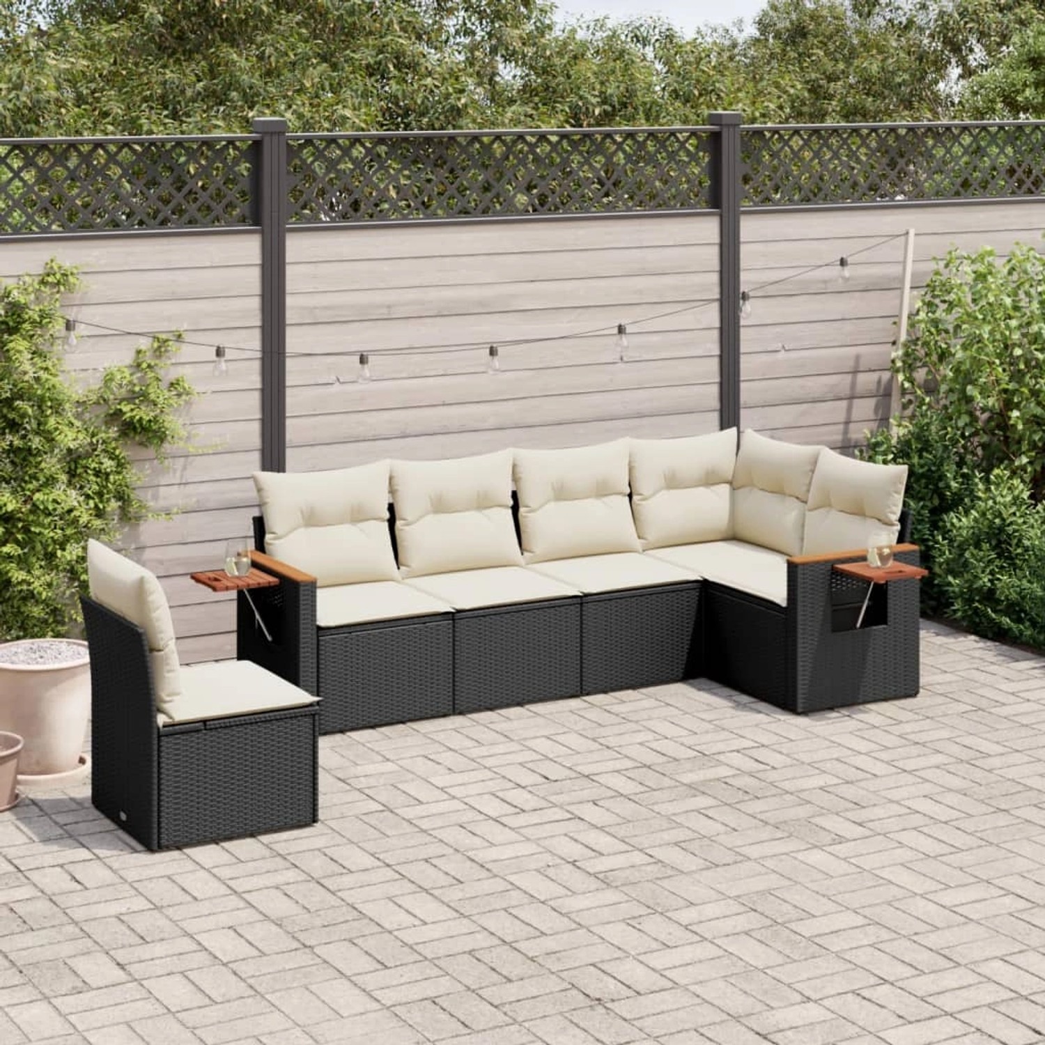 Schwarze 6-tlg. Garten-Sofagarnitur aus Polyrattan mit cremefarbenen Kissen und Beistelltischen.