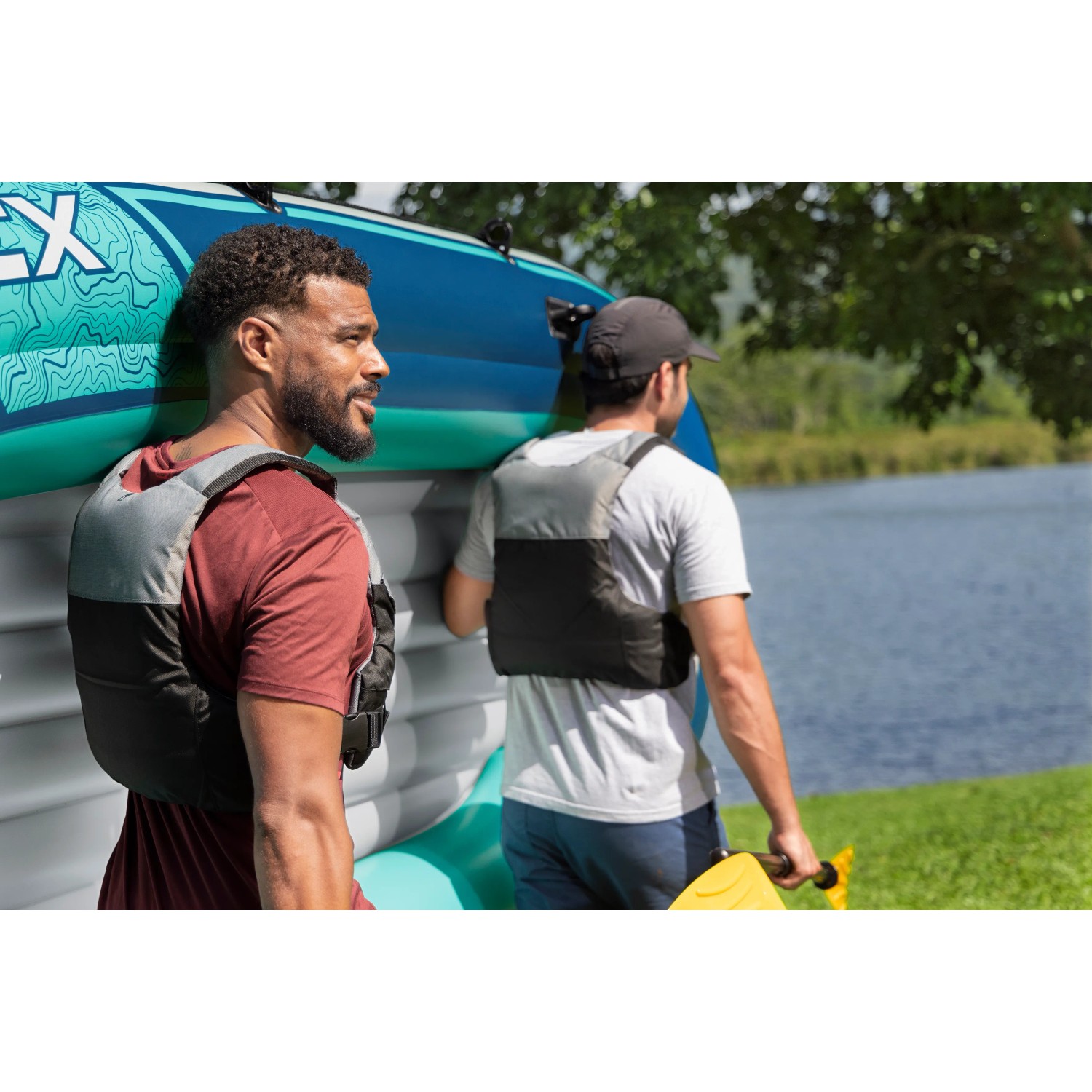 Zwei Männer tragen ein Bestway Trek X3 Schlauchboot Set am See.