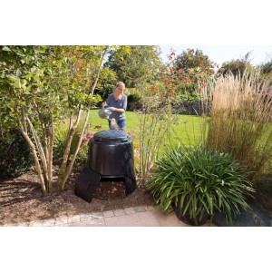 Schwarzer Garantia Komposter Eco 280 l im Garten mit Frau beim Gießen.