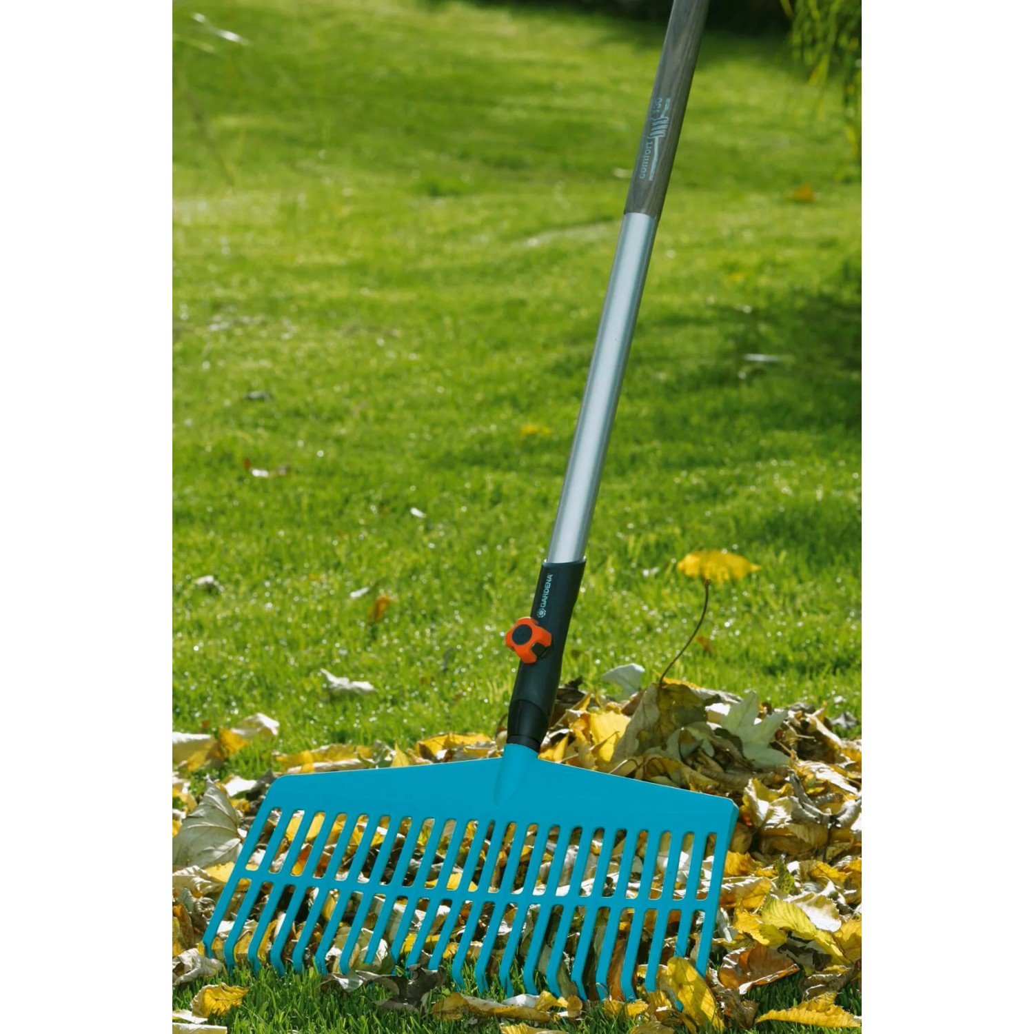 Gardena Combisystem Komplettangebot: Rechenbesen mit Holzstiel im Einsatz auf Rasen mit Laub.