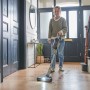 Frau nutzt Ryobi Akku-Staubsauger RSVS18BL-0 auf Holzboden. Handstaubsauger mit motorisierter Bürste und LED-Licht.