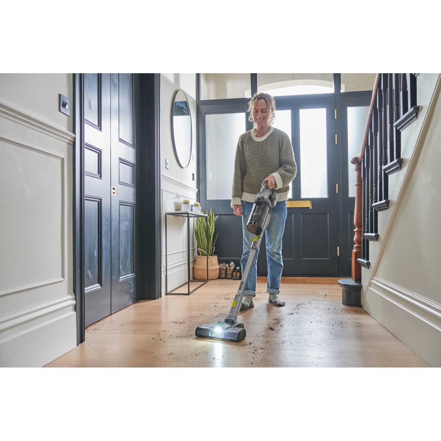 Frau nutzt Ryobi Akku-Staubsauger RSVS18BL-0 auf Holzboden. Handstaubsauger mit motorisierter Bürste und LED-Licht.