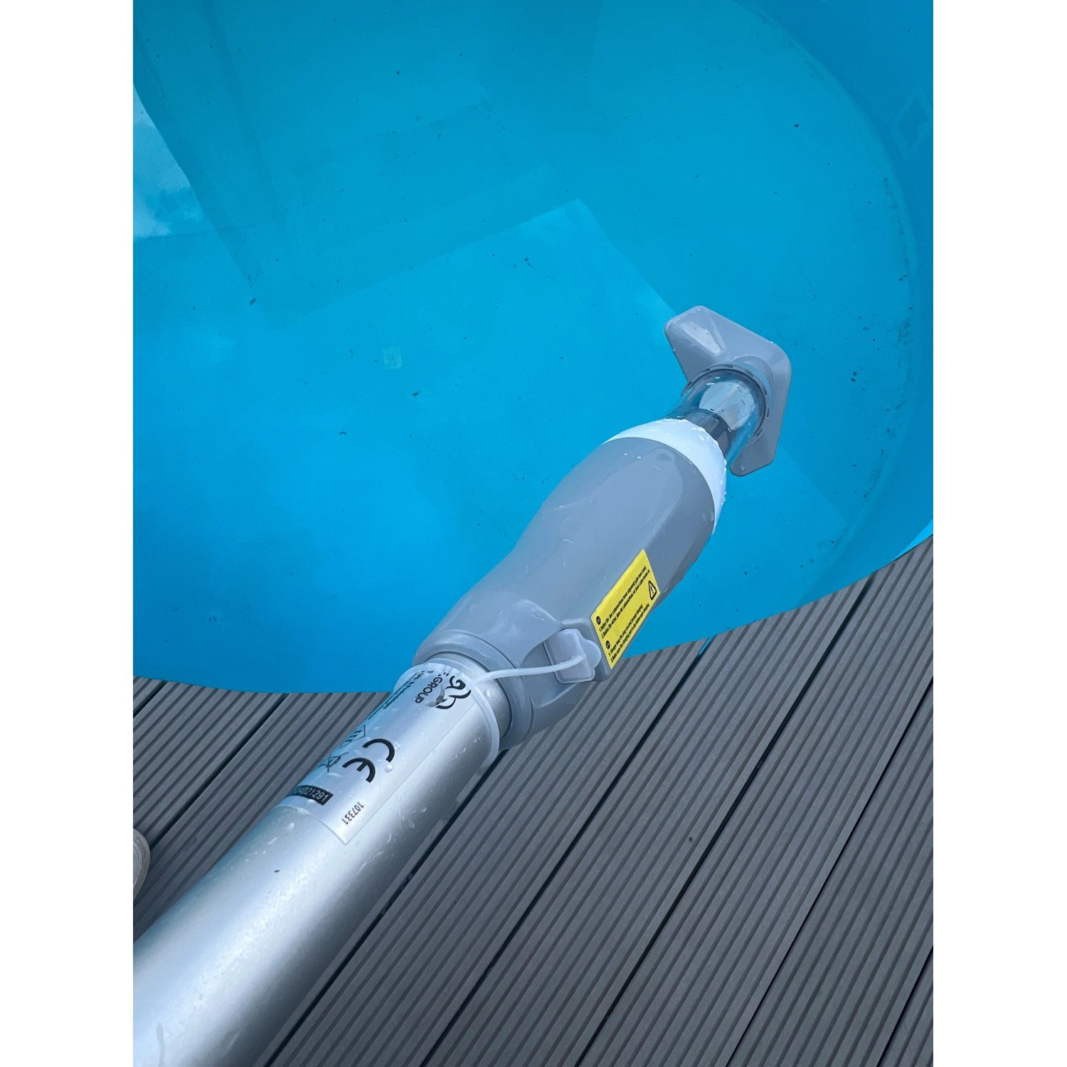 Pool-Handsauger mit Akku im Einsatz, reinigt Pool. Weiß-grauer Poolsauger mit Teleskopstange.