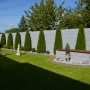 Betonzaun-Platte Casa Borsika als Sichtschutz im Garten mit Rasenfläche und Bepflanzung.