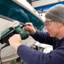 Mann schleift Boot mit Bosch Exzenterschleifer PEX 400 AE. Schleifmaschine mit Staubabsaugung.