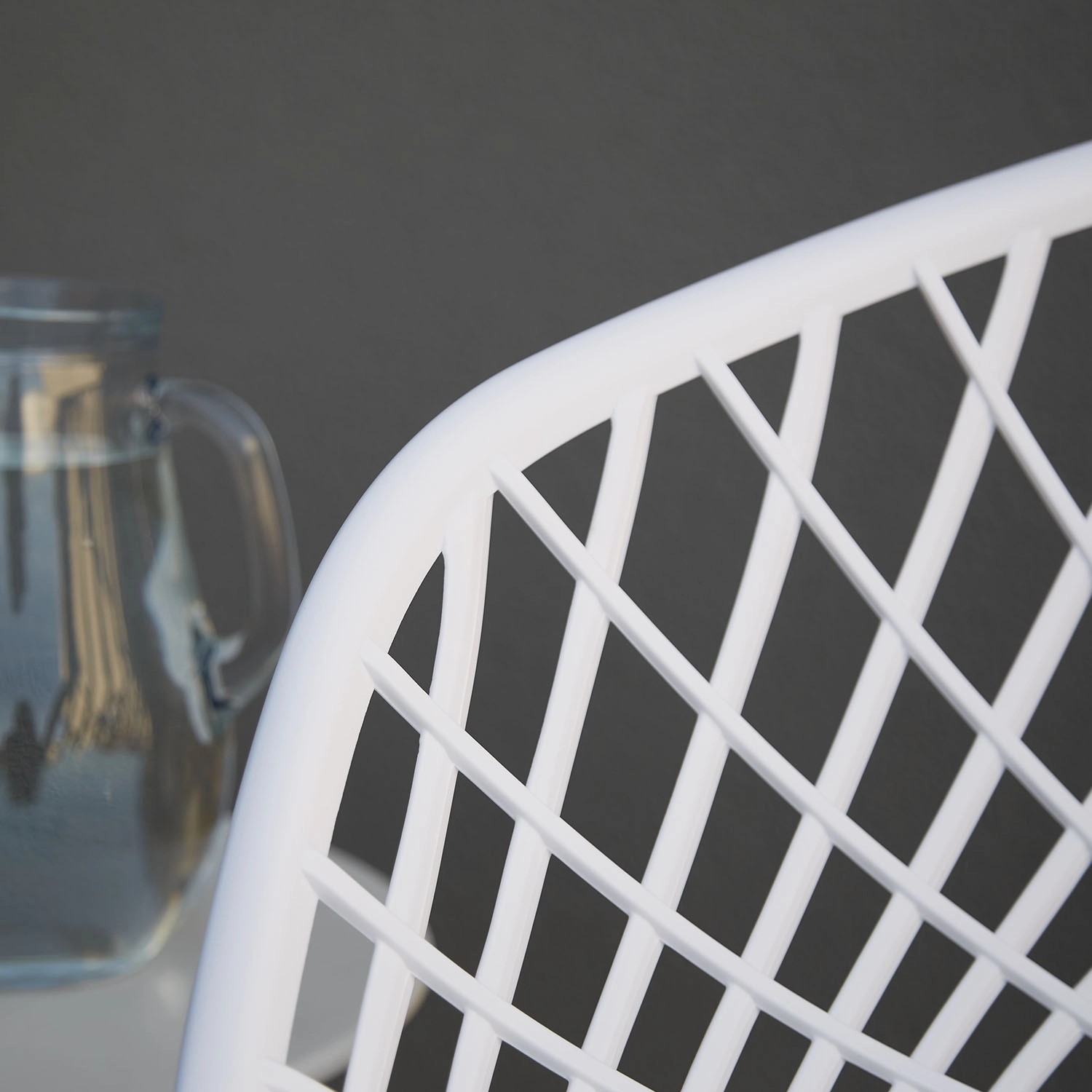 Detailansicht: Weißer Gartenstuhl aus dem 6er Set mit Gittermuster und Glaskrug.