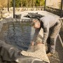 Verlegung der sandfarbenen Aquagart Steinfolie am Teichrand. Dekorative Teichfolie für naturnahe Gartenteiche.