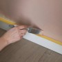 Anwendung von Wallpro Abdeckband Gelb 25mm beim Streichen einer Wand.