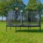 Schwarzes EXIT Allure Classic Gartentrampolin (214x366 cm) mit Sicherheitsnetz auf einer grünen Wiese.