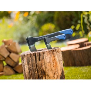 Zwei LUX Universalaxt Professional auf Holzblock, Garten im Hintergrund.