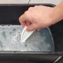 Hand hält Fugenglätter Universal in Wasser. Werkzeug zum Glätten von Fugen.