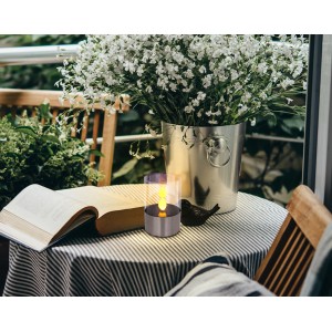 Globo LED-Solartischlampe mit Feuereffekt aus Edelstahl auf Tisch mit Buch und Blumenvase.