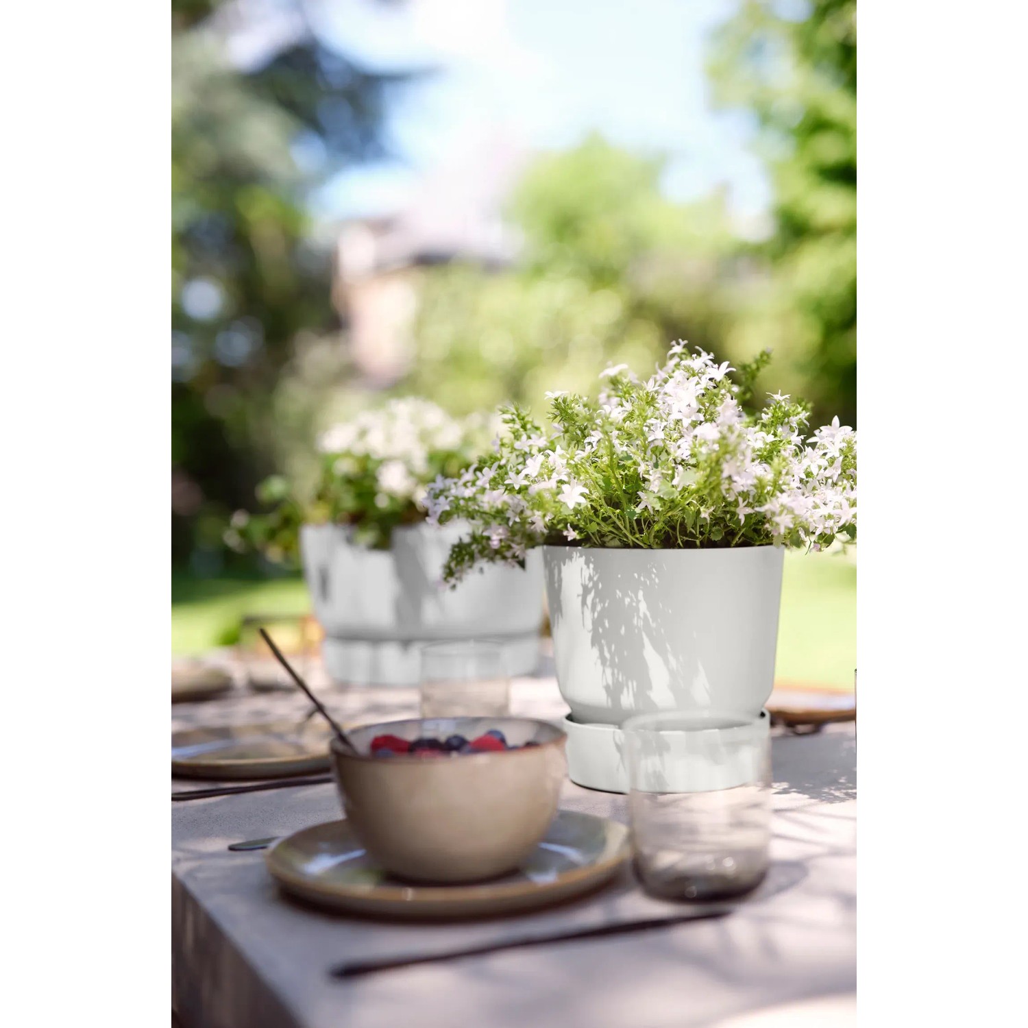 Elho Blumentopf Greenville, rund, 14 cm, Laubgrün, mit Pflanze auf einem Gartentisch.