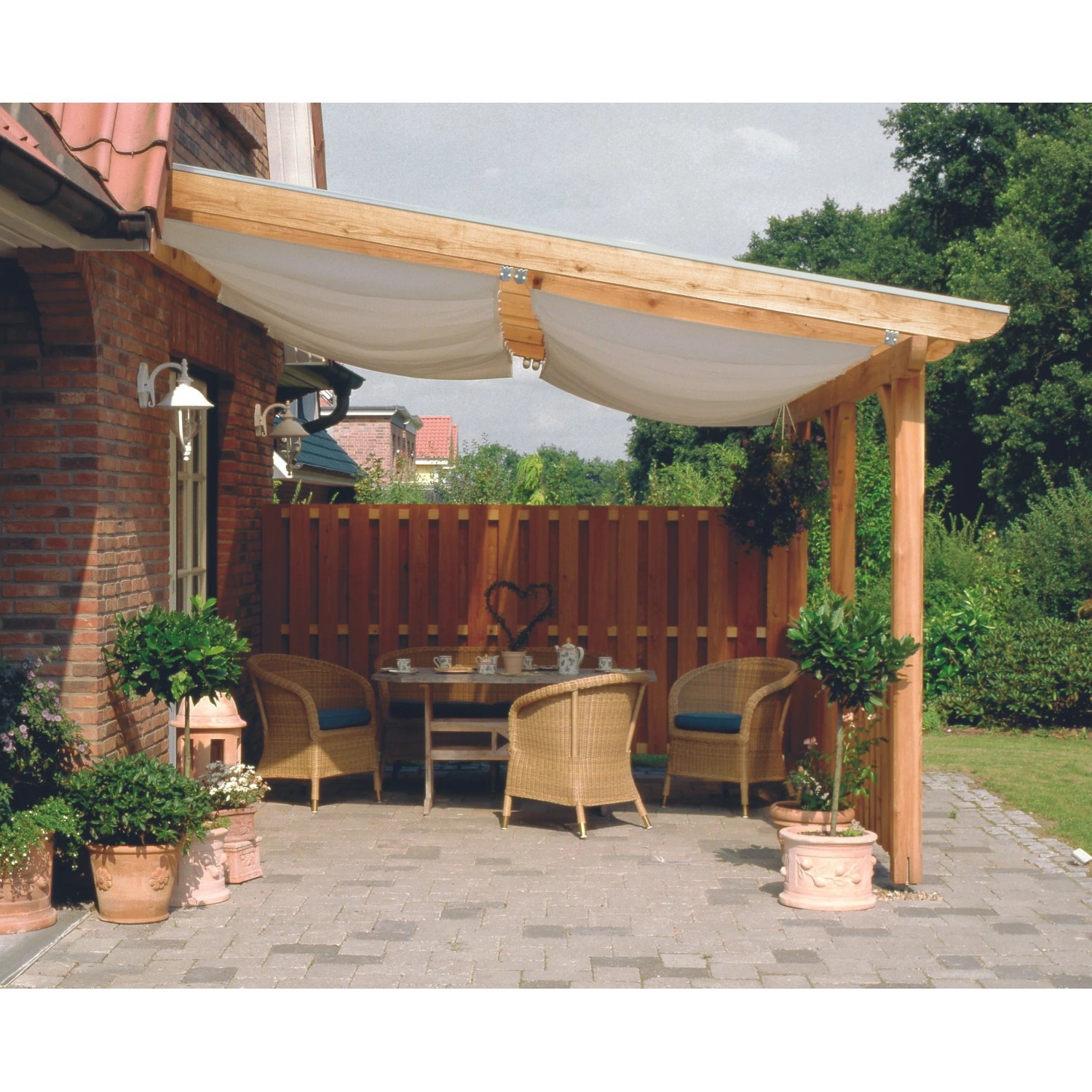 Skan Holz Seitenwand Douglasie mit Deckelschalung an Terrassenüberdachung mit Sitzgruppe im Garten.