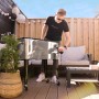 Axi Kühlwagen Retro Edelstahl 76 l im Garten mit Person, die eine Flasche öffnet.