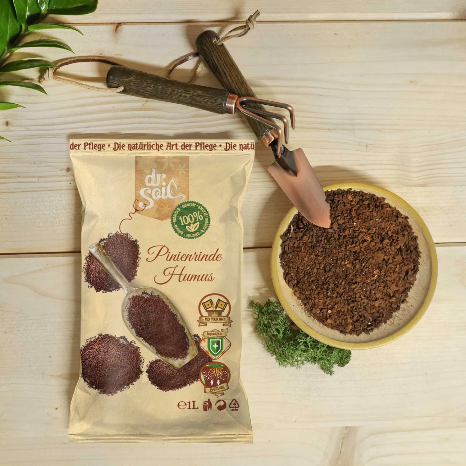Dr.Soil Pinienrinden Humus 1L Beutel mit Gartengeräten und Schale mit Rindenmulch.