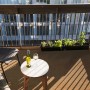 Balkon mit Primaflor Rasenteppich Green Beige, Tisch mit Wein und Pflanzenkübeln.