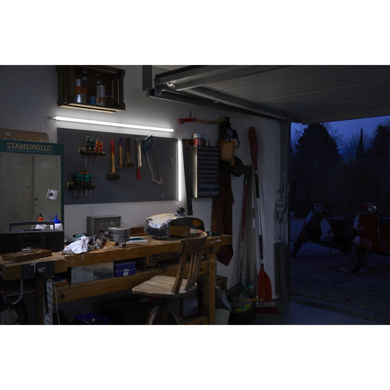 Eingeschaltete Ledvance LED-Lichtleiste Switch Batten 60cm in Werkstatt mit Werkbank.