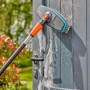 Gardena Cleansystem Stielbürste Soft in Aktion beim Reinigen einer grauen Tür mit Schaum.