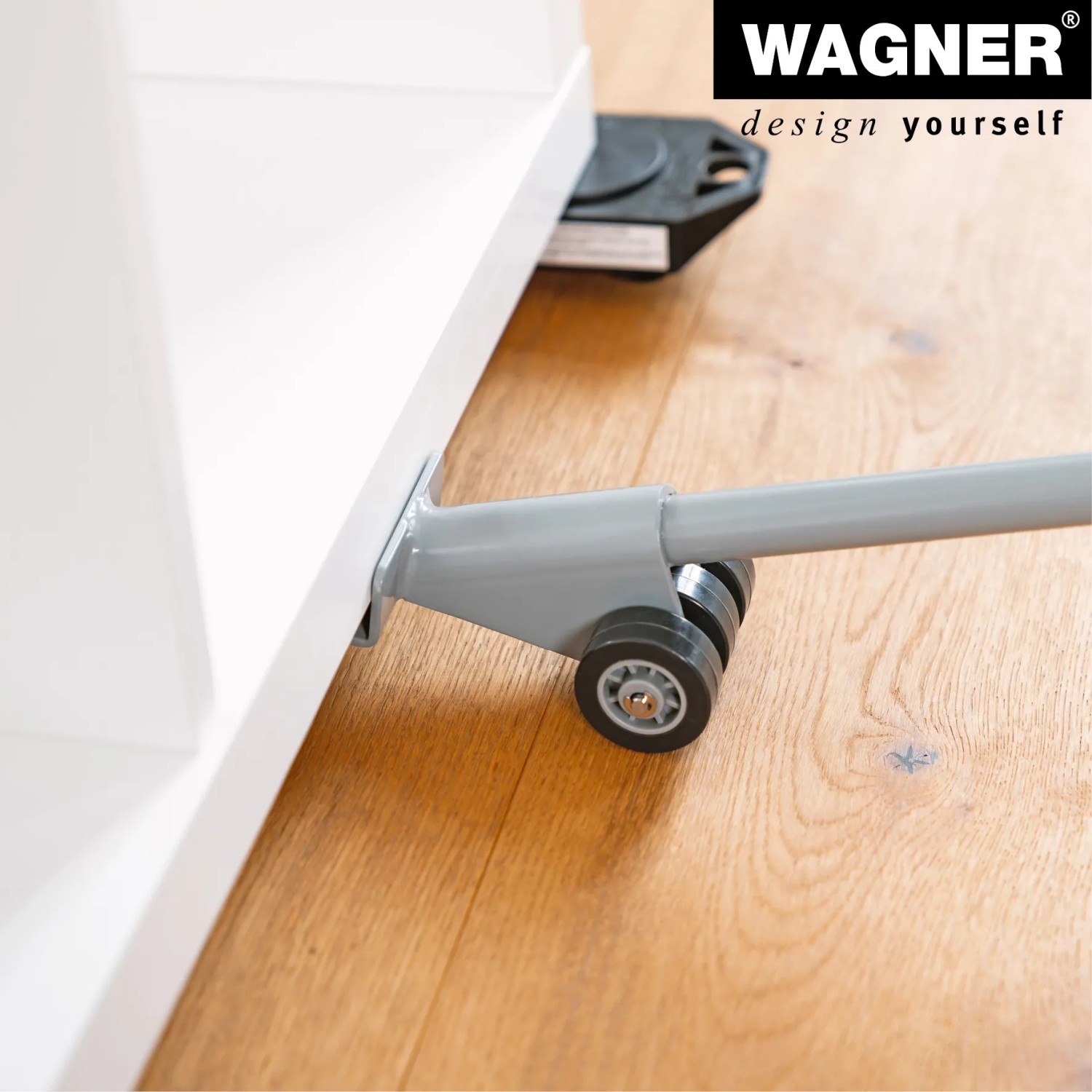 Wagner Möbelheber mit Hebeschaufel im Einsatz unter einem weißen Möbelstück auf Holzboden.