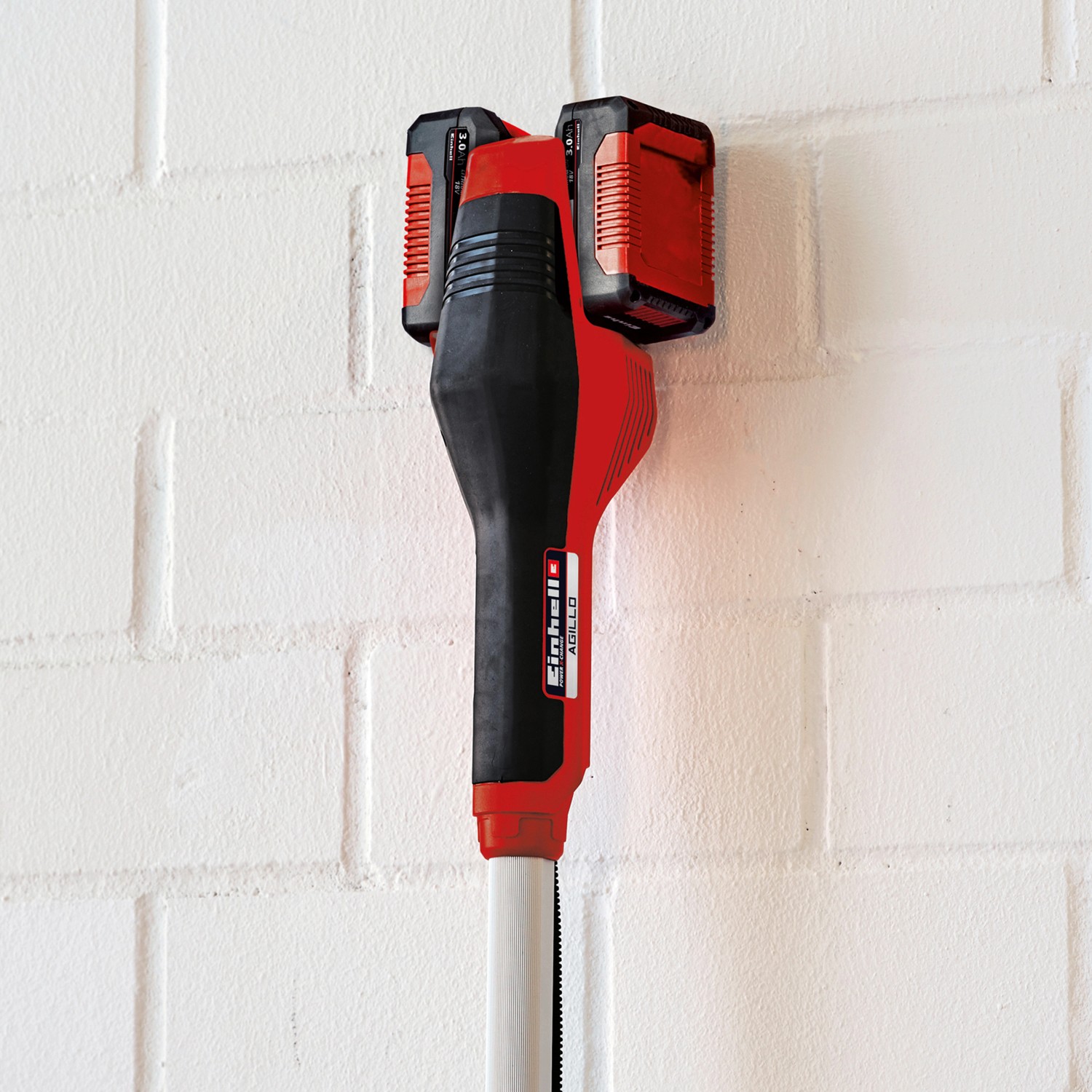 Einhell Akku-Sense Agillo mit zwei Akkus an Wandhalterung. Akku-Trimmer in Rot und Schwarz.
