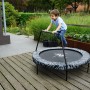 Kind springt auf EXIT Tiggy Junior Trampolin (Ø140cm) in Schwarz-Grau mit Haltebügel im Garten.