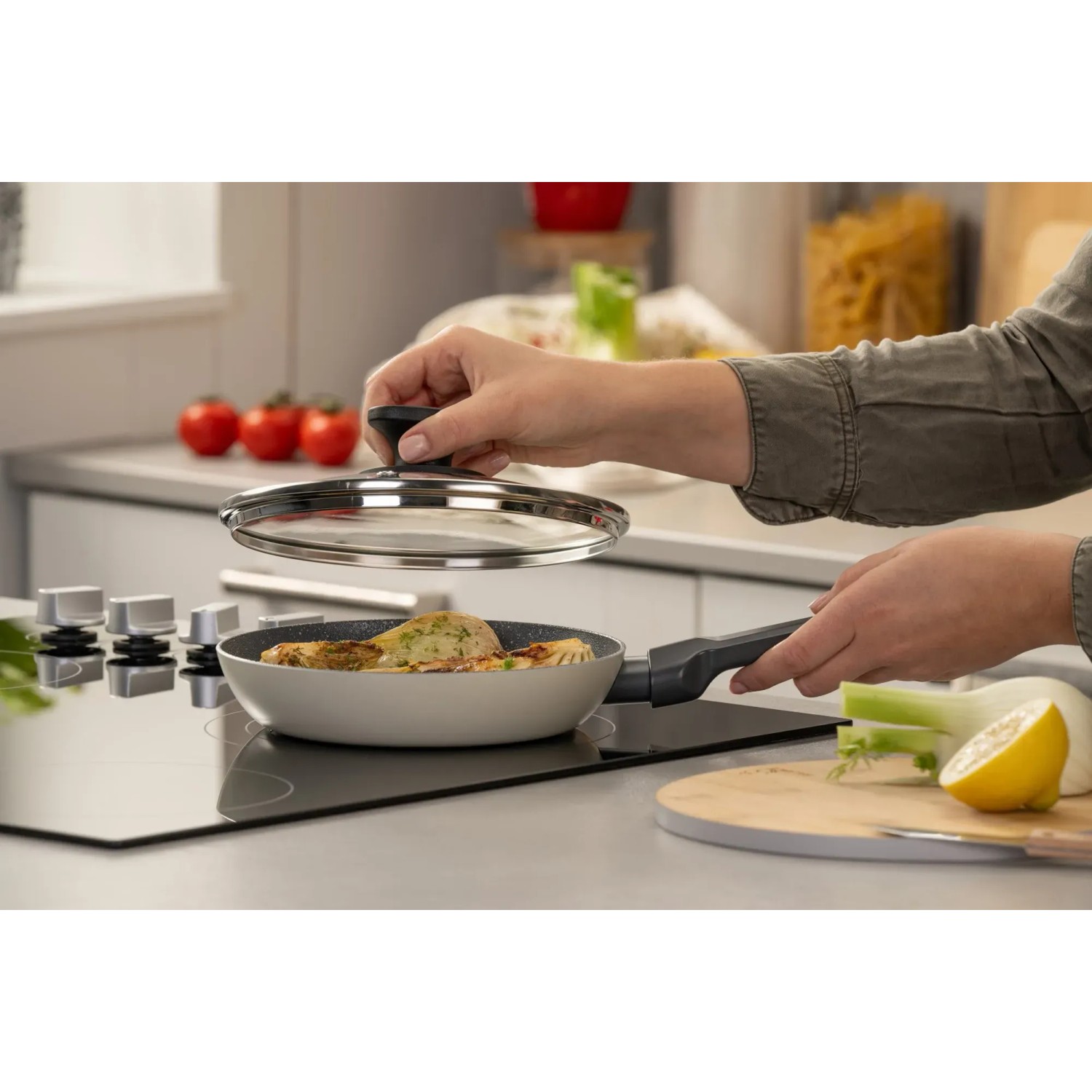 Fackelmann Pfannenglasdeckel 20 cm auf Pfanne mit Speisen, Hand hält Deckel.