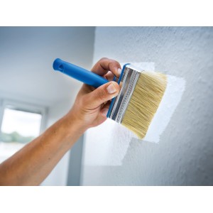 Hand streicht mit LUX Flächenstreicher (100mm) weiße Farbe auf eine Wand.