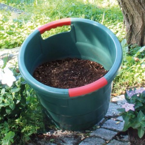Grünes Garantia Universal-Rundgefäß Toni 70 l mit rotem Griff, gefüllt mit Erde. Ideal zum Ernten und Lagern im Garten.