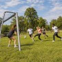 Graues Stahl-Fußballtor mit Netz im Garten, junge Erwachsene spielen Fußball. Perfekt für Sport & Training.